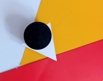 May include: A white triangle with a black circle in the center, on a yellow and red background.