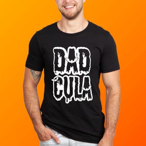 Könnte beinhalten: Schwarzes T-Shirt mit einem weißen Aufdruck, der "DAD CULA" mit tropfenden Buchstaben und Fledermäusen sagt.