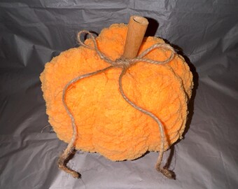 Pode incluir: Uma abóbora laranja de crochê com um caule de madeira e um barbante amarrado ao redor do topo.