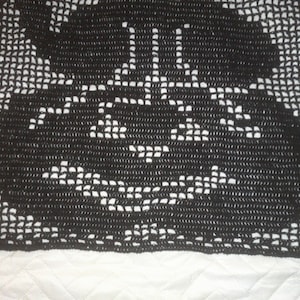 Op de afbeelding: Zwart gehaakt tafellaken met een delicaat bloemenpatroon.