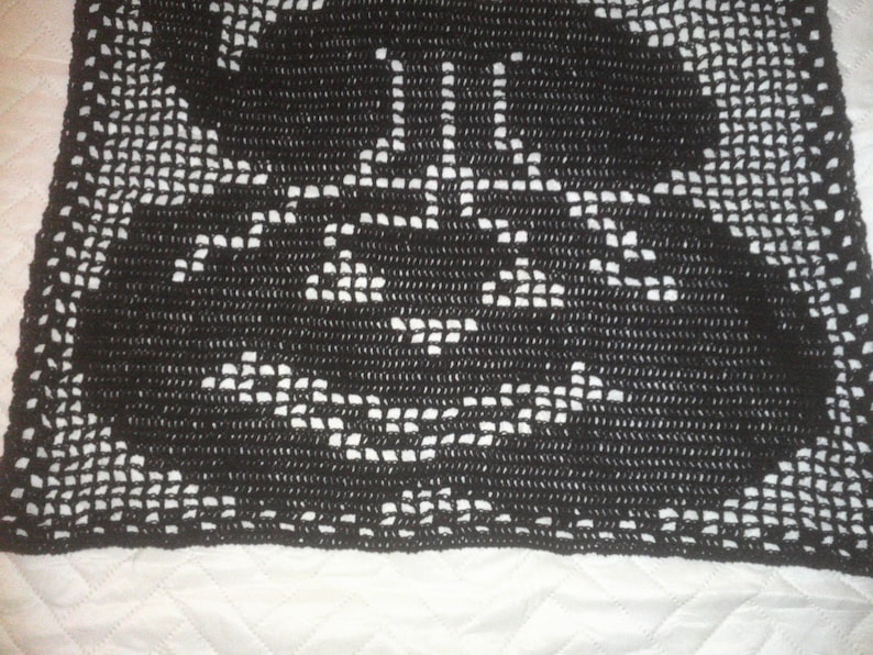 Op de afbeelding: Zwart gehaakt tafellaken met een delicaat bloemenpatroon.