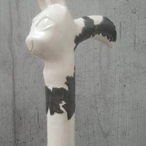 Pu&ograve; includere: Bastone in ceramica bianca con manico a forma di testa di gatto. Il volto del gatto &egrave; dettagliato con occhi e orecchie. L'asta del bastone presenta decorazioni nere. Il bastone &egrave; alto circa 91 cm.