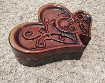 May include: A heart-shaped wooden box with intricate carvings. The box is made of dark wood and has a rich, polished finish.