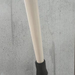 Pu&ograve; includere: Una sezione di una gamba di tavolo beige chiaro con un piedino in gomma nero. La gamba &egrave; cilindrica e angolata, su uno sfondo grigio strutturato.