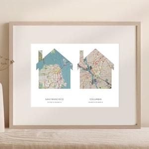May include: A framed print with two house-shaped maps of San Francisco and Columbia, Missouri. The maps are in a light blue and beige color scheme. The text below each map reads "San Francisco" and "Columbia".