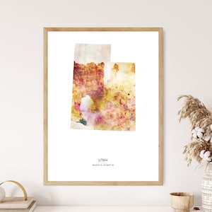 May include: A watercolor print of the state of Utah in shades of yellow, orange, and pink. The print is framed in a light wood frame and has the text "UTAH 39.3200° N, 111.0937° W" at the bottom.