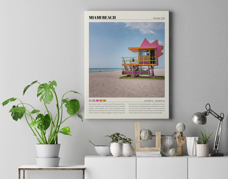 May include: A vintage-style poster featuring a pink and green lifeguard stand on a sandy beach with a blue sky and white clouds. The poster has the text "Miami Beach, Florida USA" and coordinates "25.7600&deg; N, 80.1300&deg; W".