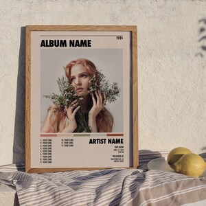 May include: A framed album cover with a woman with long red hair holding a bouquet of white flowers. The album cover is titled "ALBUM NAME" and features the artist name "ARTIST NAME". The album was released in 2024.