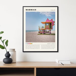 May include: A colorful lifeguard stand on a sandy beach in Miami Beach, Florida. The stand is painted pink, yellow, green, and orange. The text "Miami Beach, Florida, USA" is at the top of the image. The text "25.7607&deg; N, 80.1302&deg; W" is in the center of the image.