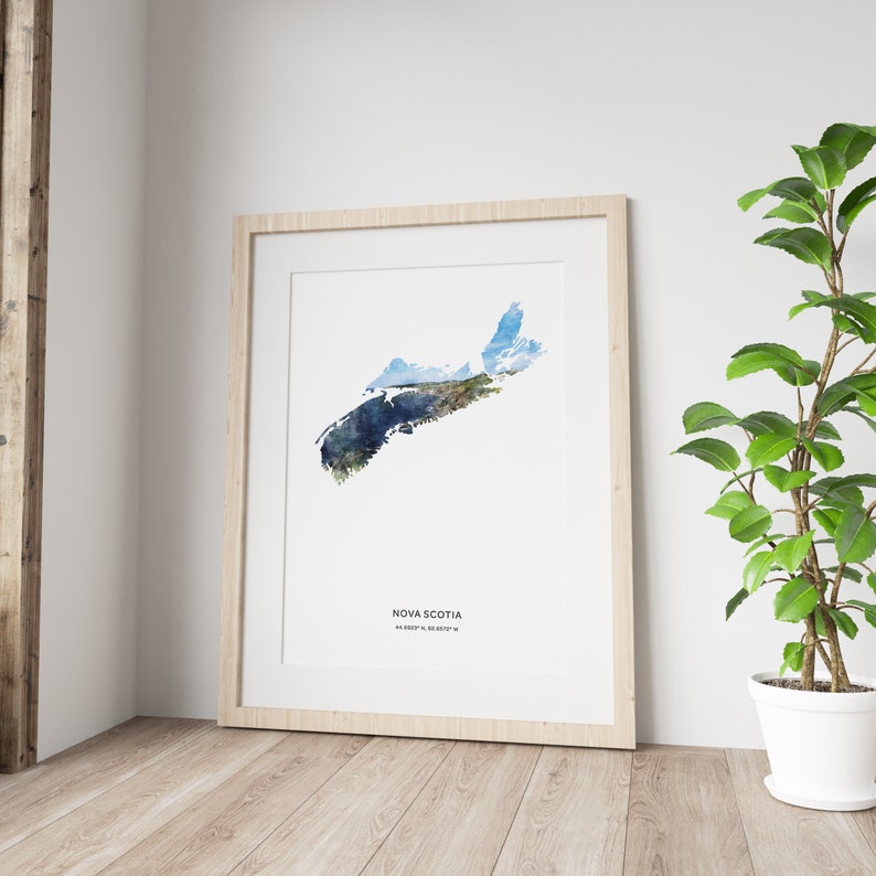 May include: A watercolor print of the outline of Nova Scotia, Canada. The print is framed in a light wood frame and is hanging on a white wall. The print is surrounded by a white mat.