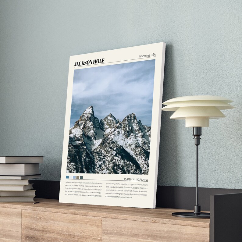 May include: A poster with a photograph of snow-capped mountains in Jackson Hole, Wyoming, USA. The poster has the text "JACKSON HOLE" and "Wyoming, USA" at the top and coordinates at the bottom.