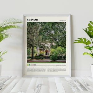 May include: A framed print of a photograph of Savannah, Georgia, USA. The image shows a street lined with trees and a white house with a red door. The text "Savannah, Georgia, USA" is at the top of the print, and the text "32.0809&deg; N, 81.0912&deg; W" is at the bottom.