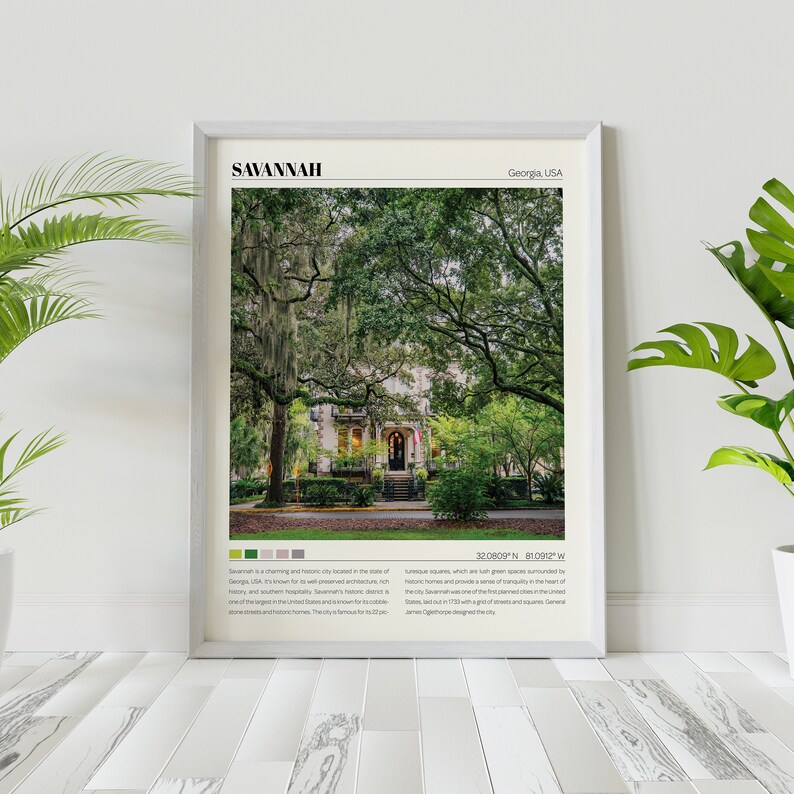 May include: A framed print of a photograph of Savannah, Georgia, USA. The image shows a street lined with trees and a white house with a red door. The text "Savannah, Georgia, USA" is at the top of the print, and the text "32.0809&deg; N, 81.0912&deg; W" is at the bottom.