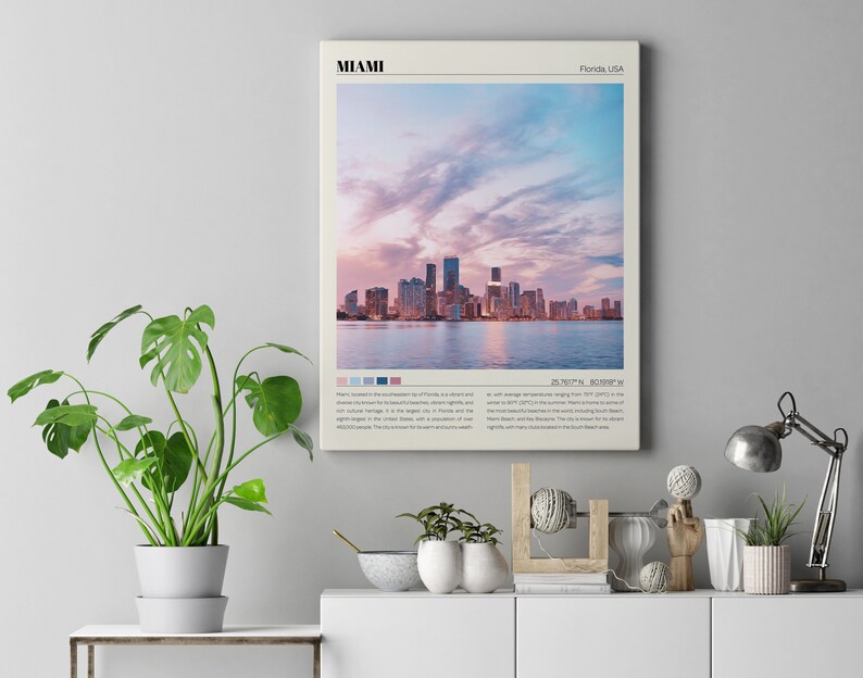 May include: A minimalist poster with a cityscape of Miami, Florida, USA. The poster features a photograph of the Miami skyline at sunset with a pink and blue sky. The poster also includes the city's name, location, and coordinates.