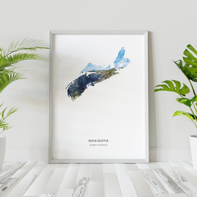May include: A watercolor print of the outline of Nova Scotia, Canada, with a blue and green color scheme. The print is framed in a light gray frame and is hanging on a white wall. The text "NOVA SCOTIA 44.6820&deg; N, 63.6872&deg; W" is printed below the map.