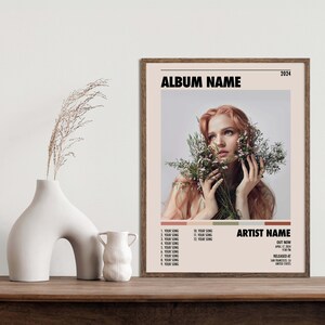 May include: Album cover art featuring a woman with long red hair holding a bouquet of white flowers. The album title is "ALBUM NAME" and the artist name is "ARTIST NAME". The album was released in 2024.