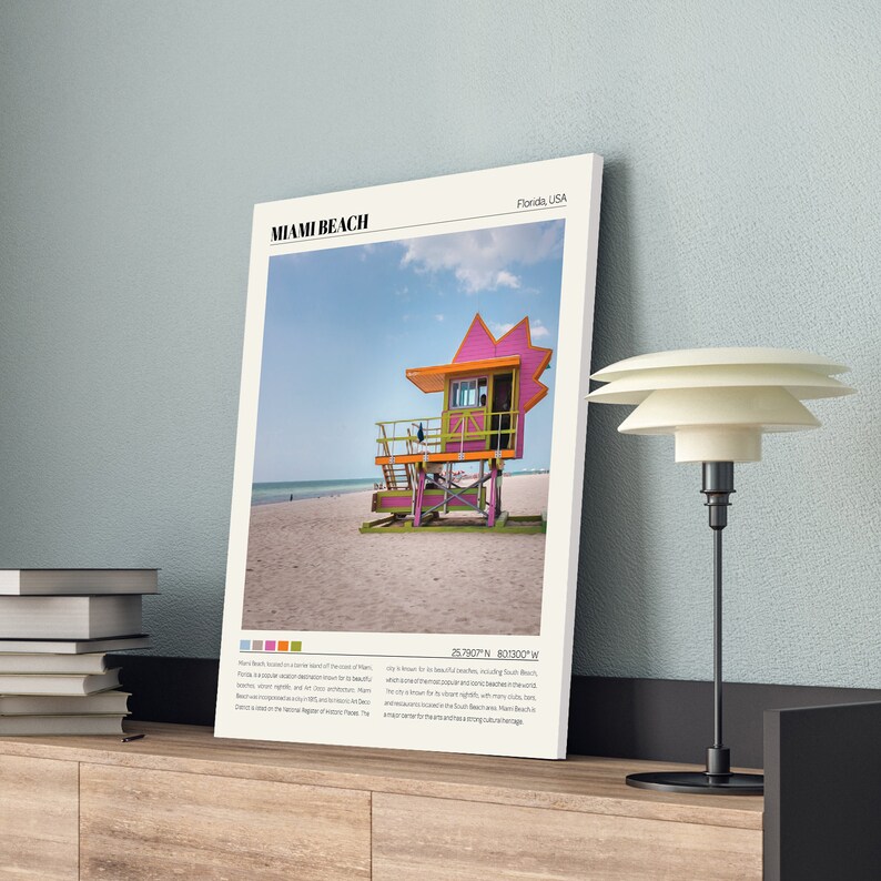 May include: A colorful lifeguard stand on a sandy beach in Miami Beach, Florida. The stand is painted pink, yellow, and green. The text "Miami Beach, Florida, USA" is at the top of the image. The text "25.7607&deg; N 80.1300&deg; W" is at the bottom of the image.