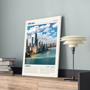 May include: A framed print of a cityscape with skyscrapers and a body of water. The print has the word "CHICAGO" in the top left corner and the coordinates "41.8781&deg; N 87.6298&deg; W" in the bottom right corner. The print is on a wooden shelf with a lamp and books.