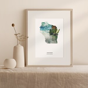 May include: A framed print of the state of Wisconsin with a scenic landscape image superimposed on the outline of the state. The text "WISCONSIN 43.0684&deg; N, 89.3888&deg; W" is printed below the image.