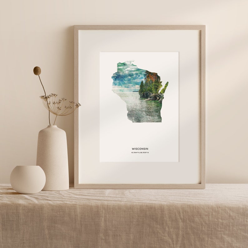 May include: A framed print of the state of Wisconsin with a scenic landscape image superimposed on the outline of the state. The text "WISCONSIN 43.0684&deg; N, 89.3888&deg; W" is printed below the image.
