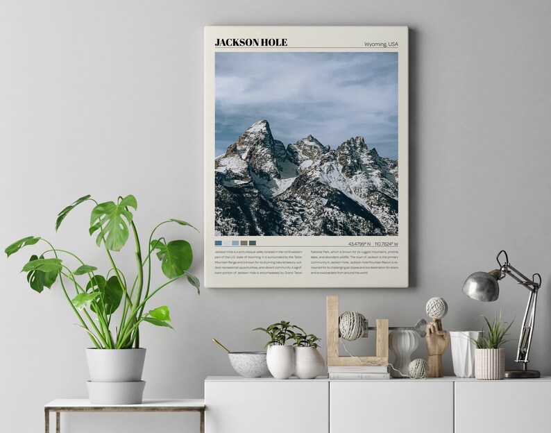 May include: A vintage-style poster with a photograph of snow-capped mountains in Jackson Hole, Wyoming, USA. The poster has a minimalist design with the text "JACKSON HOLE" and "Wyoming, USA" in a sans-serif font. The poster also includes the coordinates "43.4789&deg; N, 110.7066&deg; W".