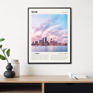 May include: A poster with a photograph of the Miami skyline at sunset. The poster has the text "MIAMI" in a black sans-serif font at the top and "Florida, USA" in a smaller font below. The poster also includes the coordinates "25.7617&deg; N, 80.1918&deg; W" and a description of Miami.