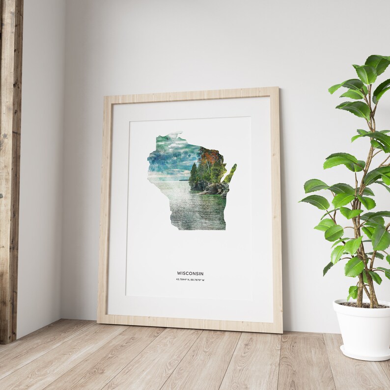 May include: A framed print of the state of Wisconsin with a scenic landscape image inside the outline of the state. The text "WISCONSIN" and the coordinates "43.0747&deg; N, 89.3841&deg; W" are printed below the image.