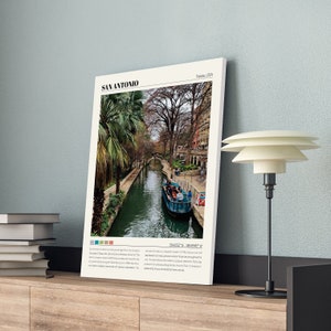 May include: A photo of the River Walk in San Antonio, Texas. The photo shows a canal with a boat full of people, palm trees, and buildings along the riverbank. The text "San Antonio, Texas, USA" is at the top of the photo.
