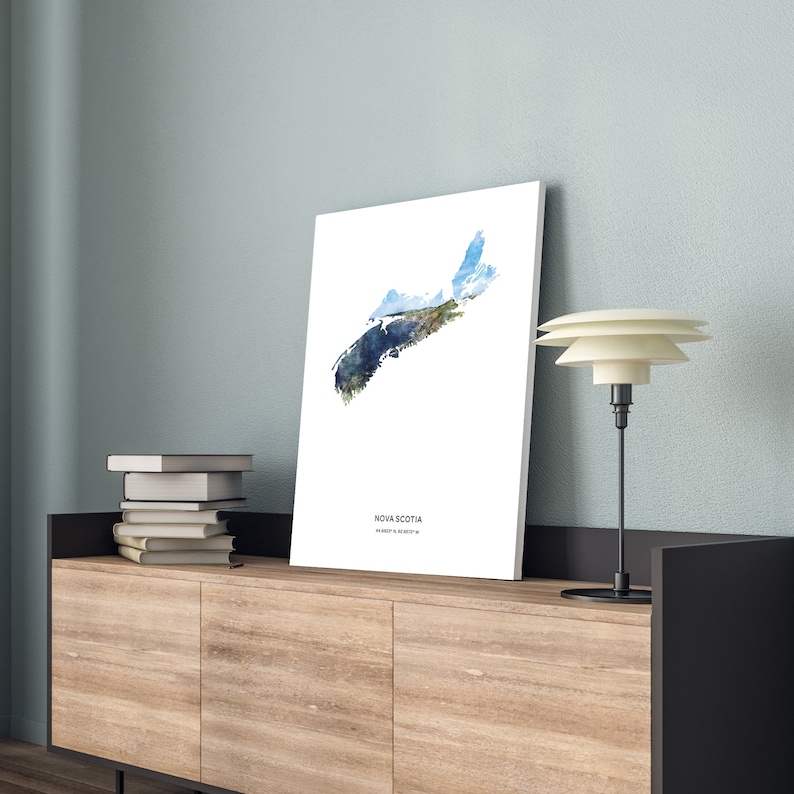 May include: A white poster with a watercolor illustration of the outline of Nova Scotia, Canada. The poster has the text "Nova Scotia" and "Happy & Cozy" printed on it.