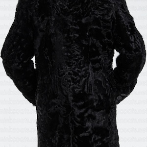 Peut inclure: Un manteau en fourrure noir à la silhouette longue et cintrée. Le manteau a une texture douce et veloutée et un design classique.