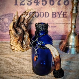 イノシシの歯の飾りが付いたアンティークの薬瓶