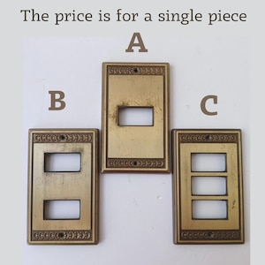 May include: Three rectangular brass light switch plates labelled A, B, and C. Plate A has one opening, B has two, and C has three. Each plate features a decorative border with a repeating pattern and screw holes at the top and bottom.