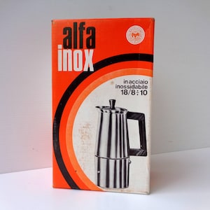以下が含まれることがあります： Alfa Inoxコーヒーメーカーの長方形の製品ボックス。箱は鮮やかなオレンジ色で、黒と白の円形のグラフィックアクセントが施されています。ステンレス製のコーヒーポットの写真とともに、「alfa inox」および「in acciaio inossidabile 18/8-10」というテキストが記載されています。
