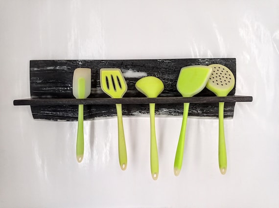 A wall-mounted utensil rack sculpted from rare bog oak (thousands of years old) fused with epoxy resin — functional kitchen storage that doubles as prehistoric art.