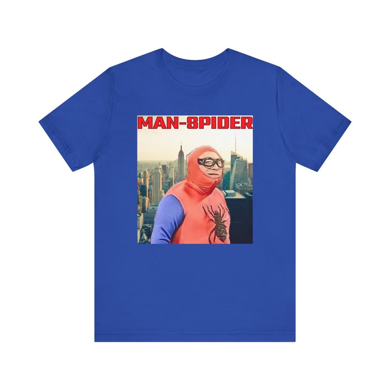 May include: Royal blue t-shirt featuring a graphic of a person in a red and blue costume with the text "MAN-SPIDER" in a red box. The graphic shows a cityscape in the background.