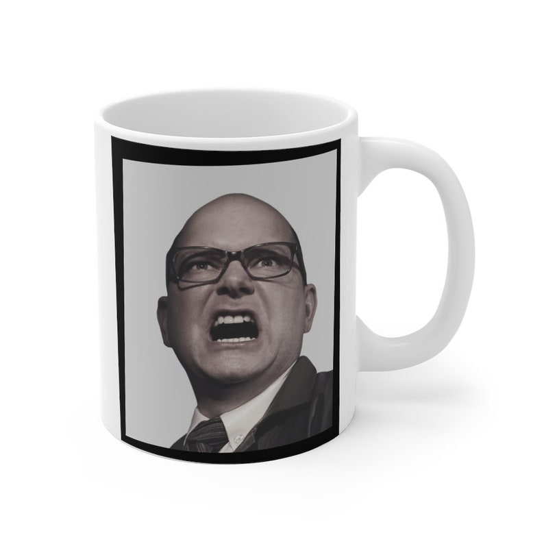 May include: White ceramic mug with a black border around a photo of a bald man with glasses shouting. The man is wearing a dark suit and tie.