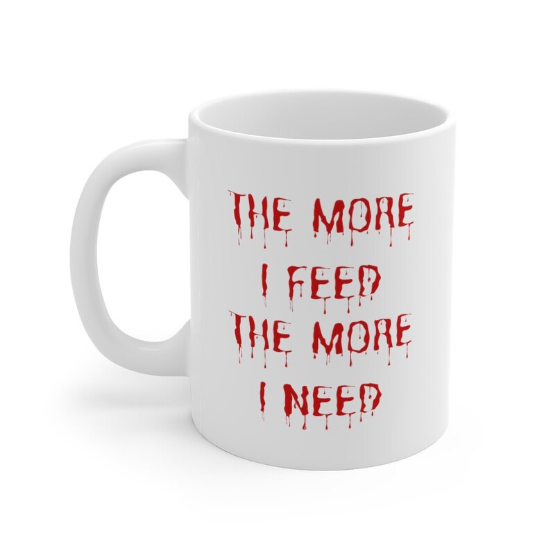 May include: White ceramic coffee mug with a red dripping text design that reads "The more I feed the more I need".