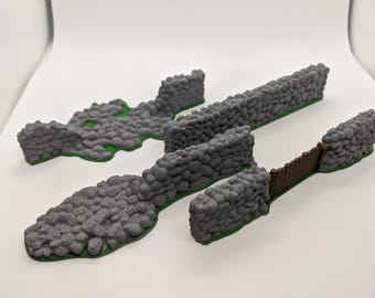 Puede incluir: Un conjunto de segmentos de muro de piedra gris en miniatura con superficies texturizadas y bases verdes. La colección incluye secciones de muro rectas, una pieza de muro curva y una pequeña puerta marrón integrada.