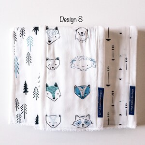 May include: Three white burp cloths with different designs. The first cloth has a blue and white pattern of trees. The second cloth has a blue and white pattern of animals, including a fox, a bear, a raccoon, a badger, and a hedgehog. The third cloth has a blue and white pattern of arrows. The text "LYTTLE BURPIES BOUTIQUE" is printed on the bottom right corner of each cloth.