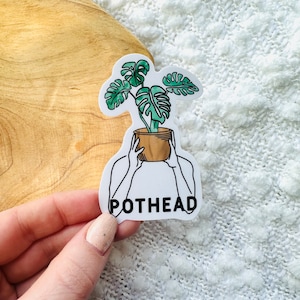 May include: White sticker with a line drawing of a person holding a potted plant with the text "POTHEAD" below.