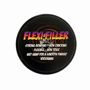 May include: A black container with a white label that reads "FLEXI FILLER" in a rainbow gradient. The label also states "STRONG BONDING - NON CRACKING, FLEXIBLE - NON TOXIC, WET SAND FOR A SMOOTH FINISH! 100GRAMS".