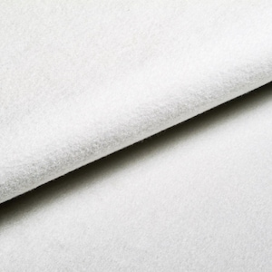 May include: Close-up of a white, soft, and textured fabric. The fabric is folded in half, showing the texture and softness of the material.