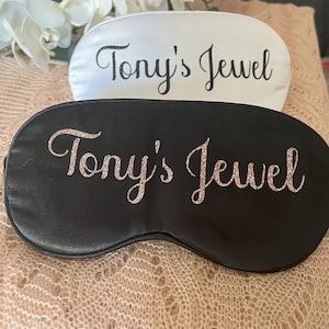 Peut inclure: Deux masques de sommeil noirs et blancs avec le texte "Tony's Jewel" en paillettes dorées sur le masque noir et en texte noir sur le masque blanc.