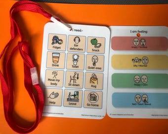 Puede incluir: Un tablero de comunicación con un cordón rojo. El tablero se divide en dos secciones: "Necesito:" con iconos para diversas necesidades, y "Me siento:" con indicadores de emociones. El tablero está diseñado para ayudar a la comunicación.