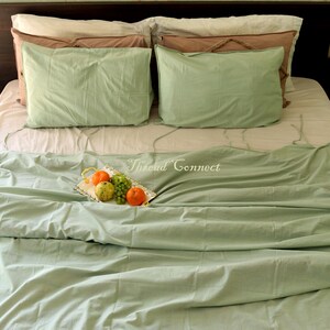 K&ouml;nnte beinhalten: Ein gr&uuml;nes Bett mit einem wei&szlig;en Bettbezug und zwei gr&uuml;nen Kissen. Ein silbernes Tablett mit Obst liegt auf dem Bett. Der Text "Thread Connect" ist auf dem Bett sichtbar.