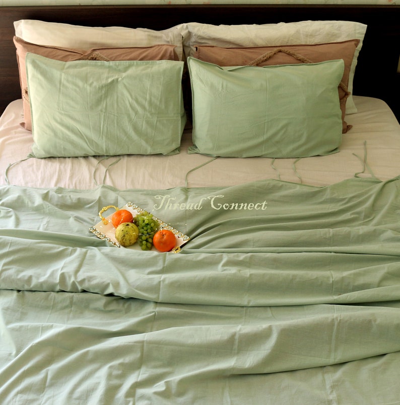 K&ouml;nnte beinhalten: Ein gr&uuml;nes Bett mit einem wei&szlig;en Bettbezug und zwei gr&uuml;nen Kissen. Ein silbernes Tablett mit Obst liegt auf dem Bett. Der Text "Thread Connect" ist auf dem Bett sichtbar.