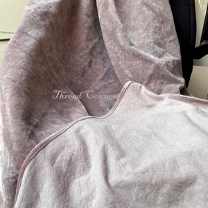 Pu&ograve; includere: Primo piano di un tessuto di velluto rosa antico dall'aspetto morbido e strutturato. Il tessuto &egrave; drappeggiato, creando pieghe e ombre. Il testo "Thread Connect" &egrave; visibile nell'immagine.