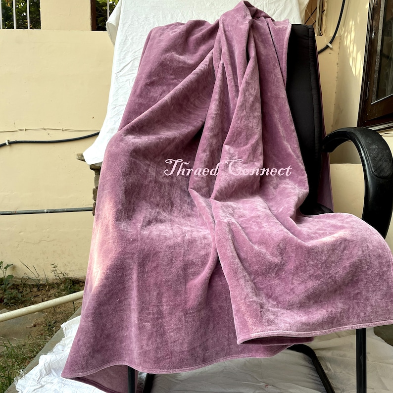 Pu&ograve; includere: Un tessuto di velluto rosa polveroso drappeggiato su una sedia nera. Il tessuto &egrave; morbido e strutturato, con pieghe e ombre visibili. Il testo "Thraed Connect" &egrave; visibile sul tessuto.