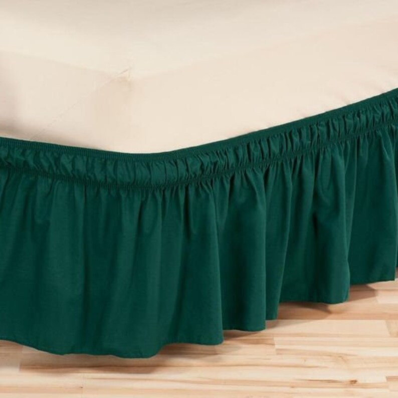 May include: A dark green bed skirt with a ruffled edge. The skirt is made of a soft, smooth fabric and is designed to cover the box spring of a bed.