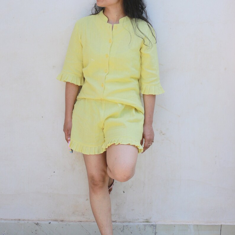 May include: A yellow linen short set with a button-up top and ruffled shorts.
